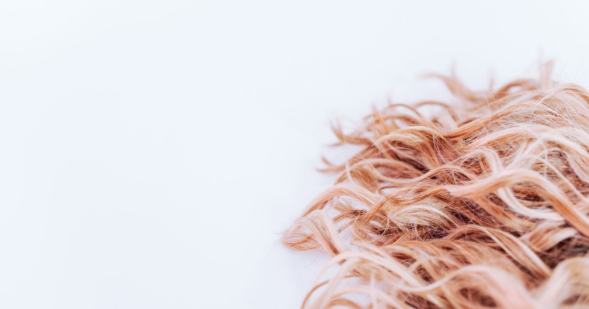 Detailed close-up of wavy blonde hair texture on a light background, showcasing elegance and style.