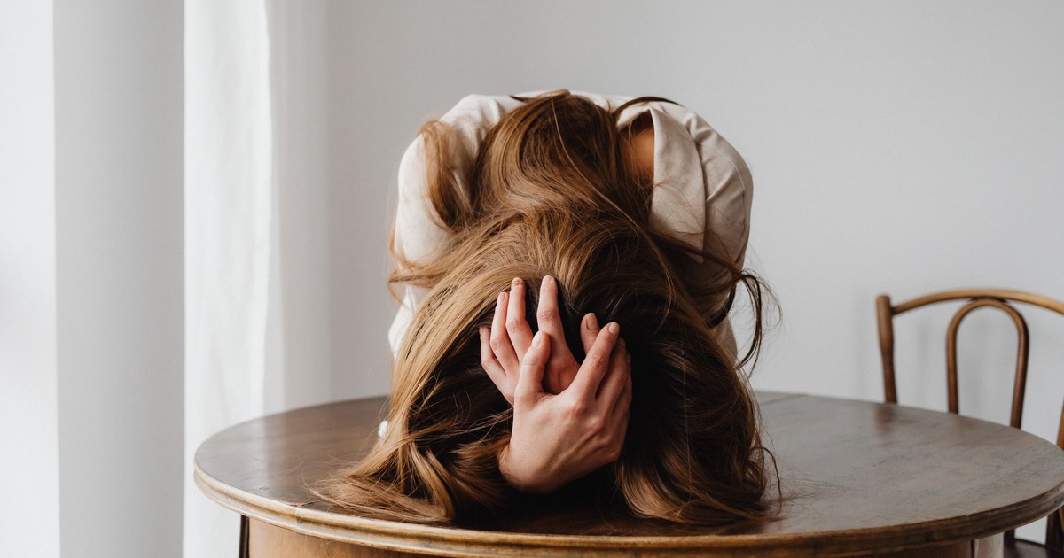 A woman showing despair with her head down on a table, indicating stress.