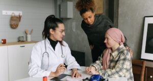 A doctor consulting with cancer patient and friend at home, offering support.