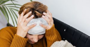 Doctors Sound Alarm Over Popular Outdoor Activity Linked to Devastating Brain, Facial Injuries Woman with head injury holding her head in pain indoors.