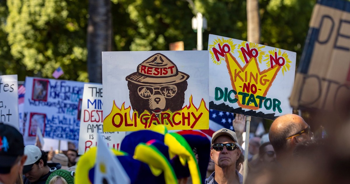 Dynamic protest scene in Sacramento highlighting political dissent with anti-oligarchy signs.