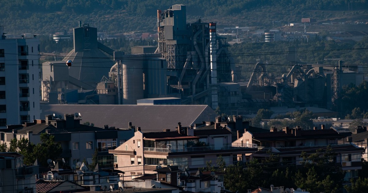 A view of industrial buildings alongside residential rooftops in İzmir, Turkey, showcasing urban contrast.
