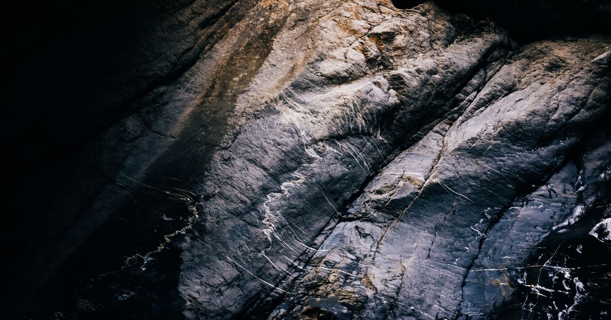 A detailed view of a textured rock surface with natural light and shadows creating patterns.