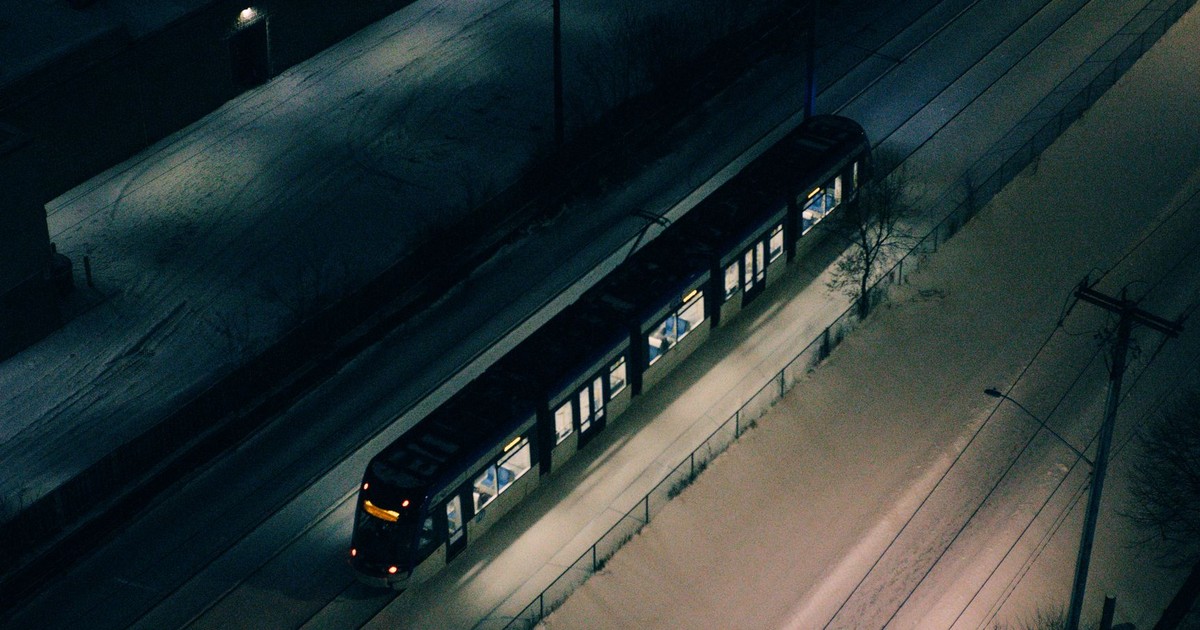 A night-time aerial shot of a train traveling through snow-covered Kitchener, Ontario.