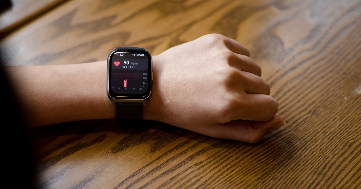 Close-up of a smartwatch displaying a heart rate of 90 bpm on a person's wrist.