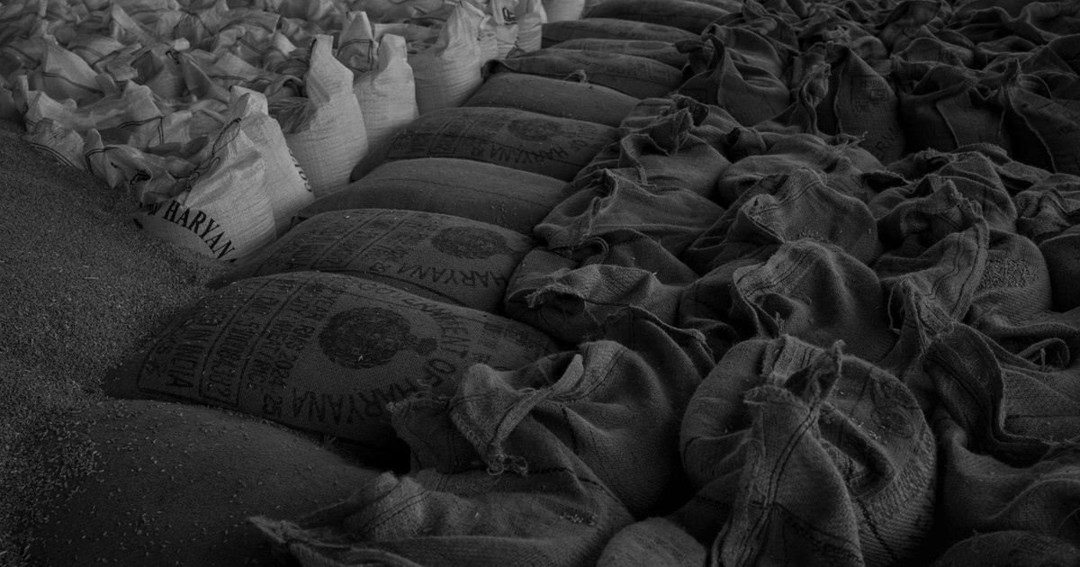 Black and white image of neatly stacked sacks filled with grain, showcasing market storage.