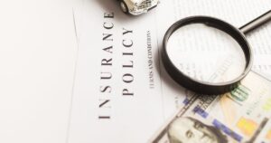 Medicare's Hidden Two-Year Lookback Rule Can Catch Retirees by Surprise Close-up image of an insurance policy with a magnifying glass, money, and toy car.