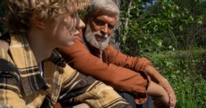 This Millennial's Take on Baby Boomers Is Going Viral — And the Data Backs Him Up A senior man and young boy enjoying a peaceful moment in a lush forest setting.