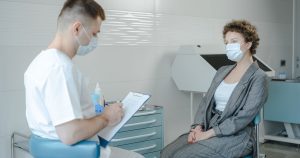 A doctor in a face mask consults a patient in a clinic, reflecting the new normal.