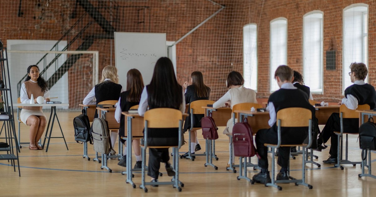 Students in a classroom setting facing a teacher, engaged in education.