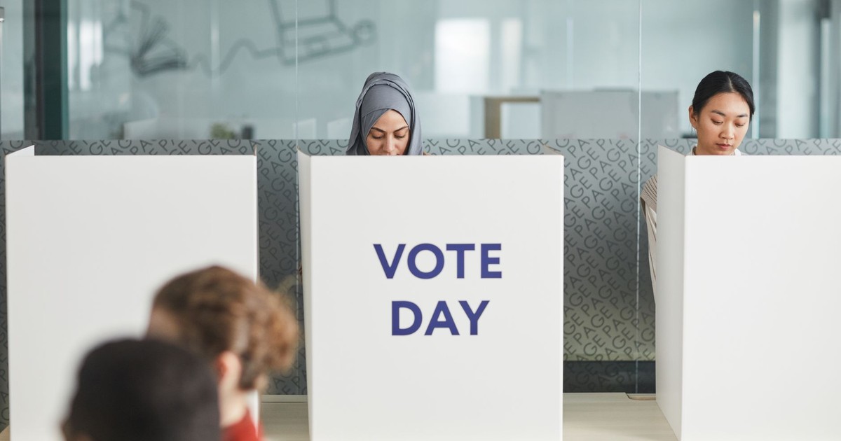 Two women casting their votes in an office during election day, focusing on diversity and civic engagement.