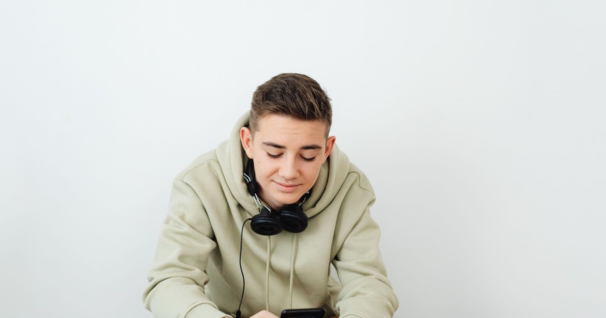 Young person enjoying technology, wearing casual clothes and headphones.