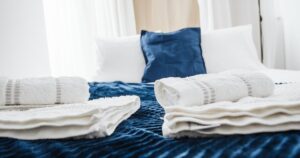 Why You Should Always Wash Guest Room Sheets Before Guests Arrive Elegant hotel room showcasing neatly arranged fresh towels and plush bedding in a contemporary setting.