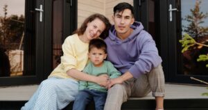 A joyful family of three enjoying quality time on their porch, sharing smiles.