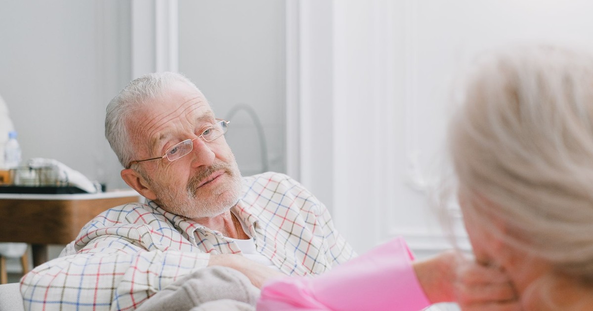 Elderly couple in conversation indoors; relaxed and intimate setting.