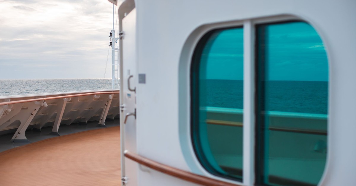 Peaceful view from a cruise ship deck with ocean reflection through a green window.