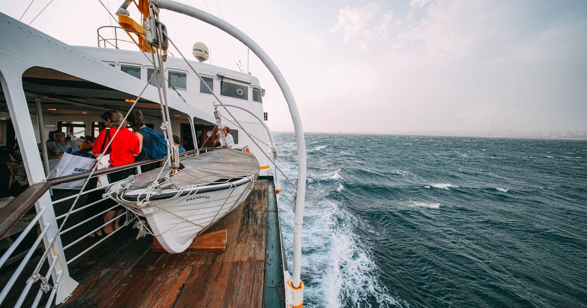 Passengers enjoying the ocean view from a ship deck during the day.