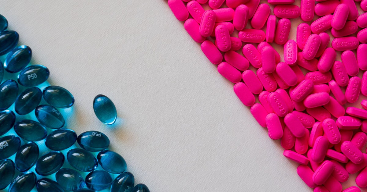 Close-up of blue gel capsules and pink tablets on a white background.