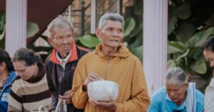 Elderly people in a community gathering, sharing gifts outdoors with a warm communal spirit.