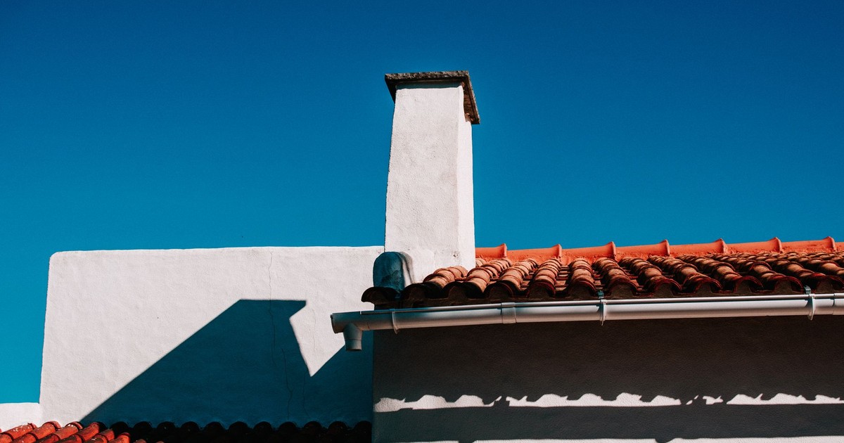 Low angle view of a traditional terracotta rooftop under a clear blue sky in summer.