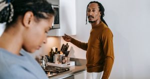 Young black couple in casual outfit standing at kitchen and arguing with each other at home