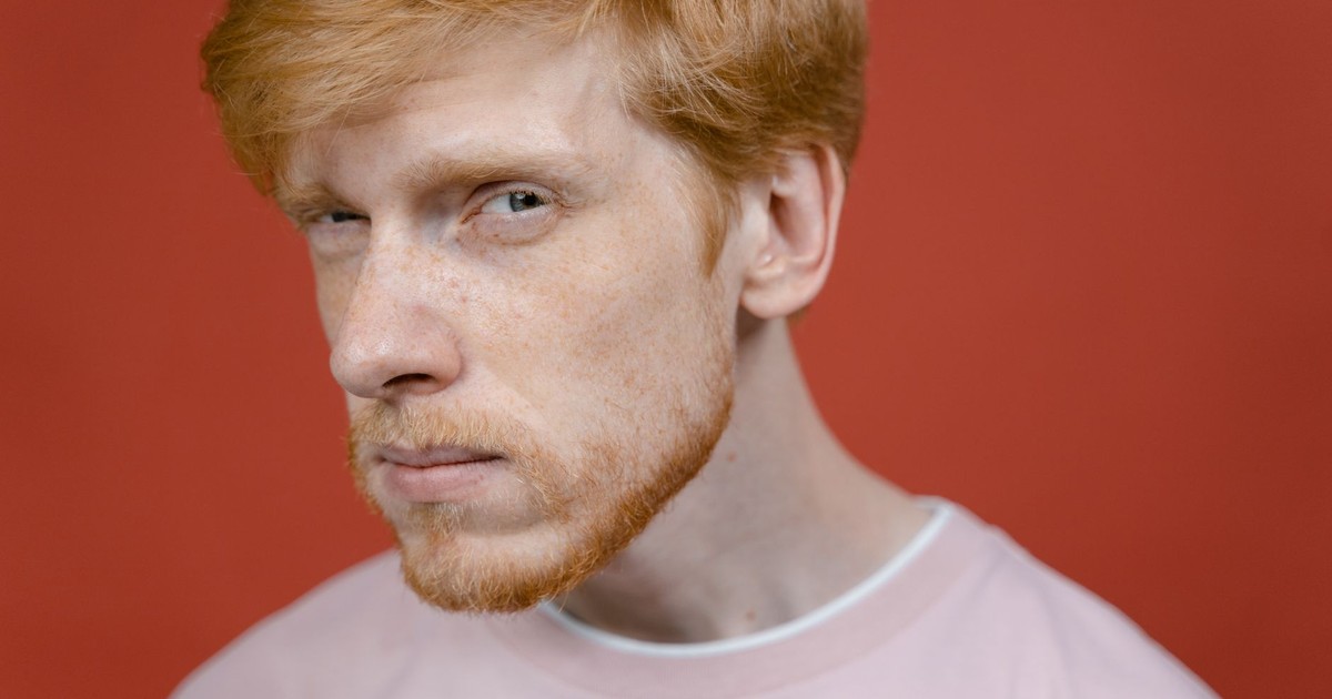 Portrait of a skeptical man with red hair and freckles, showcasing a doubtful expression.