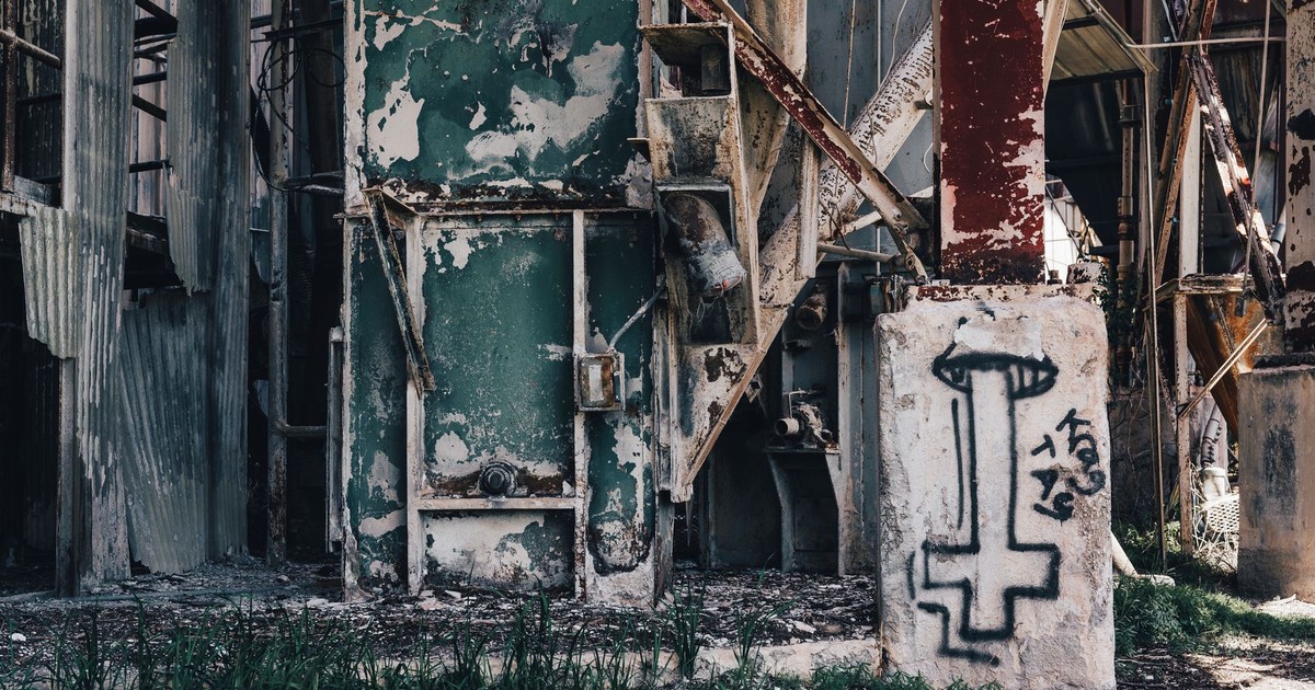 Close-up of a decaying factory facade covered in rust and graffiti.