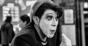 A captivating black and white portrait of a mime artist performing indoors, showcasing expressive facial expressions and makeup.