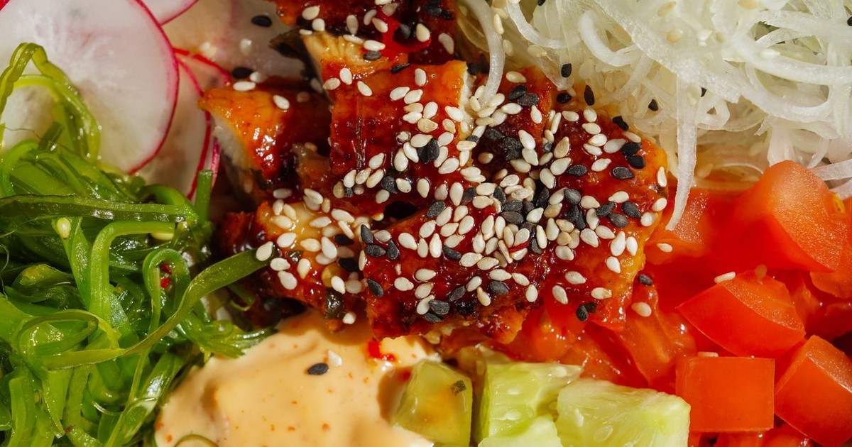 Colorful poke bowl with sesame-topped salmon, vegetables, and sauce, perfect for a healthy meal.
