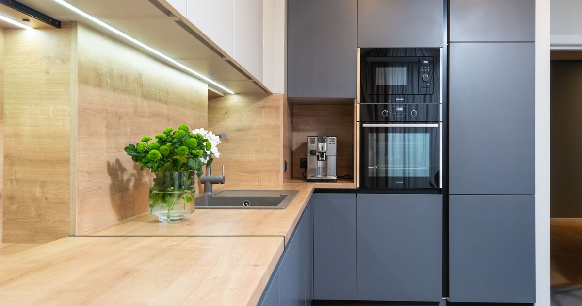 Creative design of kitchen with flowers in vase on table against coffeemaker and oven built in cupboard at home