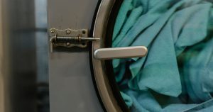 Detailed view of a commercial washing machine with blue fabric inside during a wash cycle.