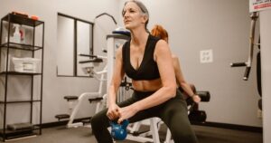 The Simple Functional Test Doctors Use to Help Predict Longevity After 75 Active senior woman performing kettlebell squats for strength training at indoor gym.