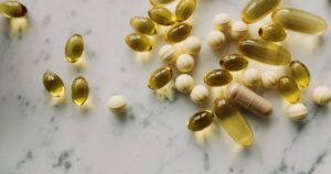 Common Vitamin May Cut Glaucoma Risk by 66%, New Study Finds Variety of supplements and capsules scattered on a marble surface, suitable for healthcare themes.