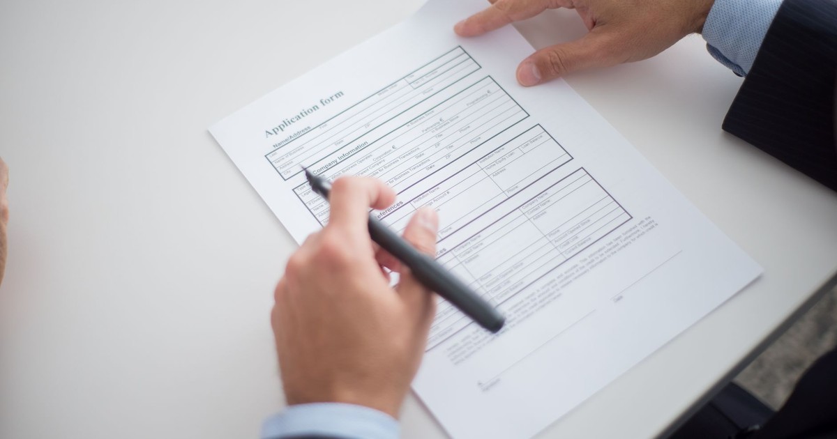 Close-up of a business professional reviewing an application form at a desk.