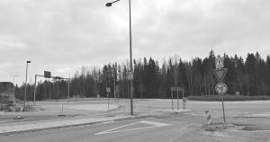 State Removes Controversial Sign From Highway After Veterans Complain Black and white image of an empty roundabout with traffic signs and trees in the background.