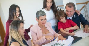 States That Can Legally Force You to Pay for Your Elderly Parents' Debts A family discusses property plans with a realtor indoors, focused on purchasing a new home.