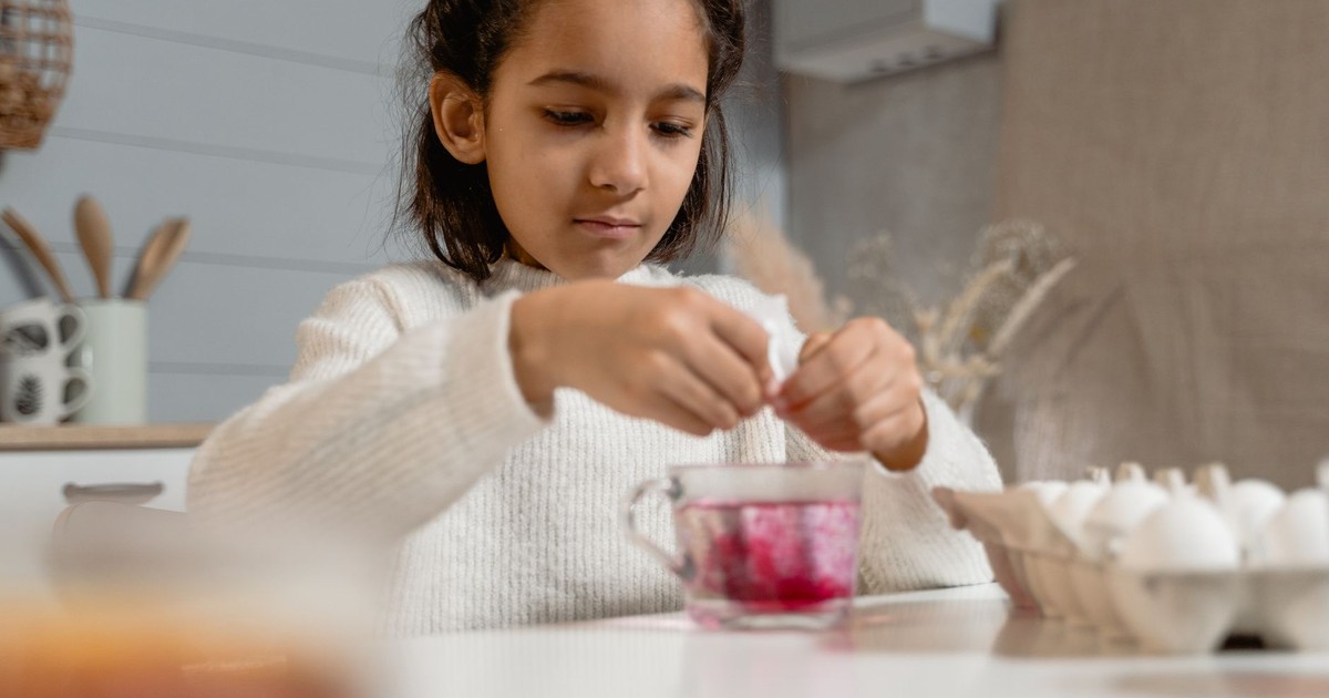 A child in a cozy kitchen setting dyes eggs, showcasing creativity and family traditions.