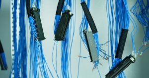 Close-up of blue ethernet cables hanging in a data center, highlighting technology connections.