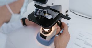 Close-up of a scientist examining samples under a microscope in a laboratory setting.