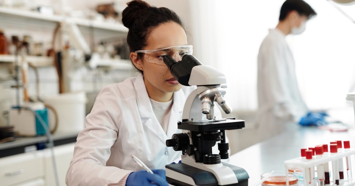 A scientist in a lab coat using a microscope in a modern laboratory setting.