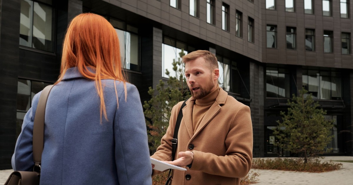 Two business professionals in conversation outside an urban office building.