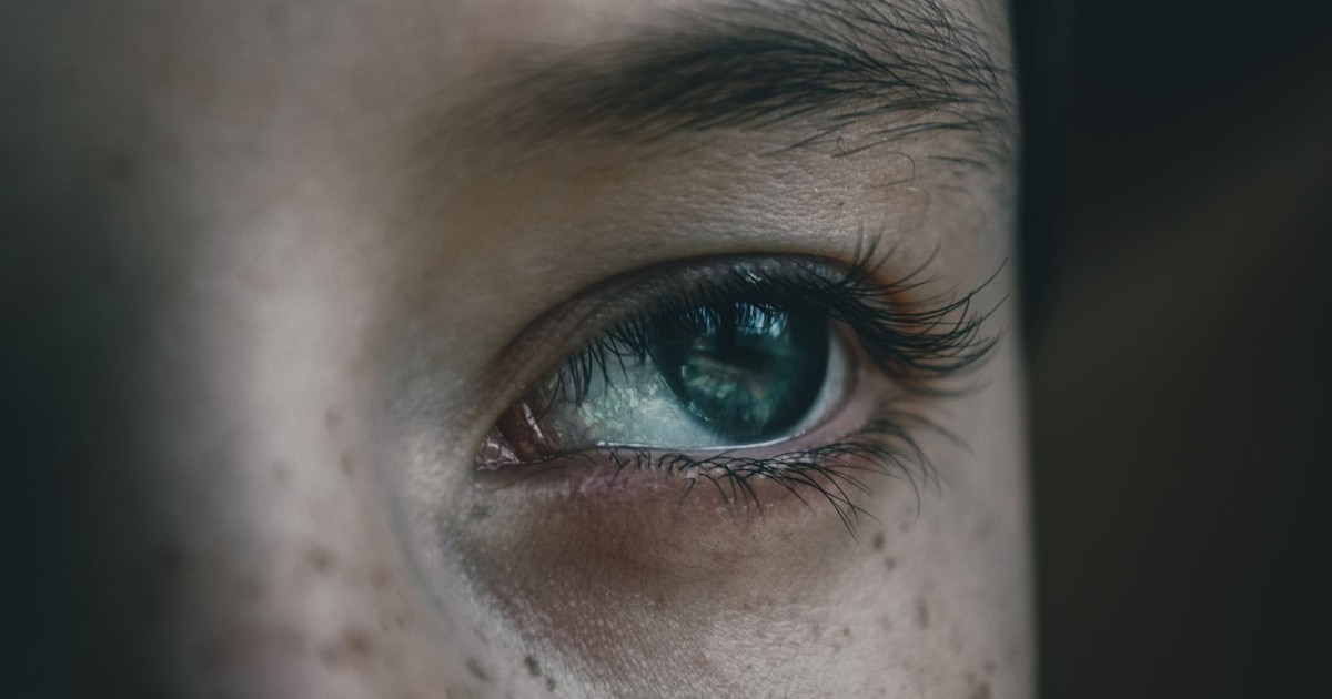 Closeup face of crop anonymous boy with brown freckles looking away with thoughtful gaze on blurred background