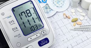 8 Foods That Could Be Making Your Blood Pressure Worse Close-up of a digital blood pressure monitor with ECG printout, pills, and medical tools.