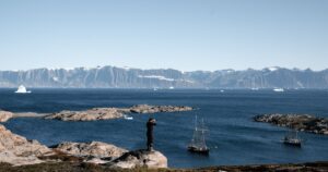 Breathtaking view of Arctic Ocean with sailboats, icebergs, and majestic mountains.