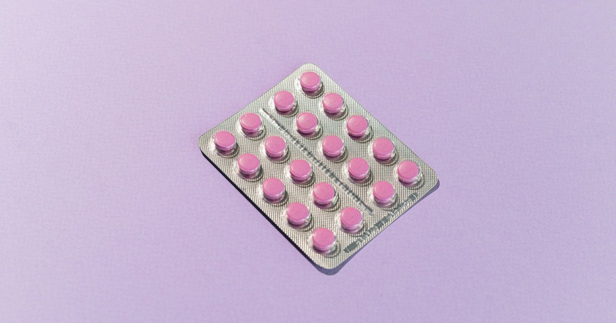 Blister pack containing pink tablets on a lavender background, highlighting healthcare theme.
