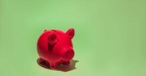 Trump Accounts Launch on July 4: Who Qualifies for the $1,000 Payment? Red piggy bank on a green background symbolizing savings and financial planning.