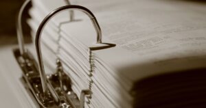 The Government's Own Report Contradicts Trump's Social Security Promise Detailed sepia close-up of a binder filled with documents, emphasizing texture.