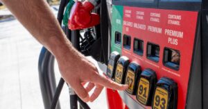 Person selecting fuel type at gas starion pump. High gas prices concept
