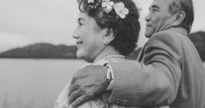 Elderly couple sharing a romantic moment by the serene lake, symbolizing enduring love.