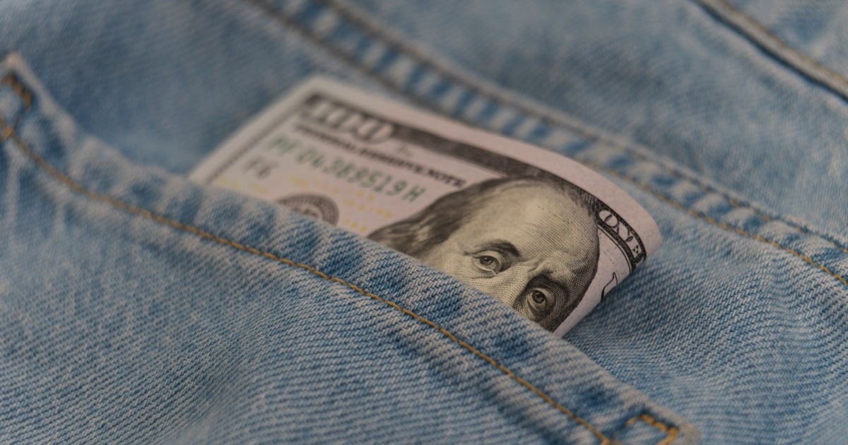 Close-up of a 100 dollar bill in a denim pocket, symbolizing finance and savings.